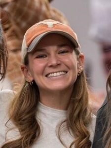 Person standing and smiling wearing a UT baseball cap